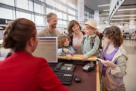 O familie tânără cu trei copii la ghișeul de check-in austriac de la aeroportul din Viena