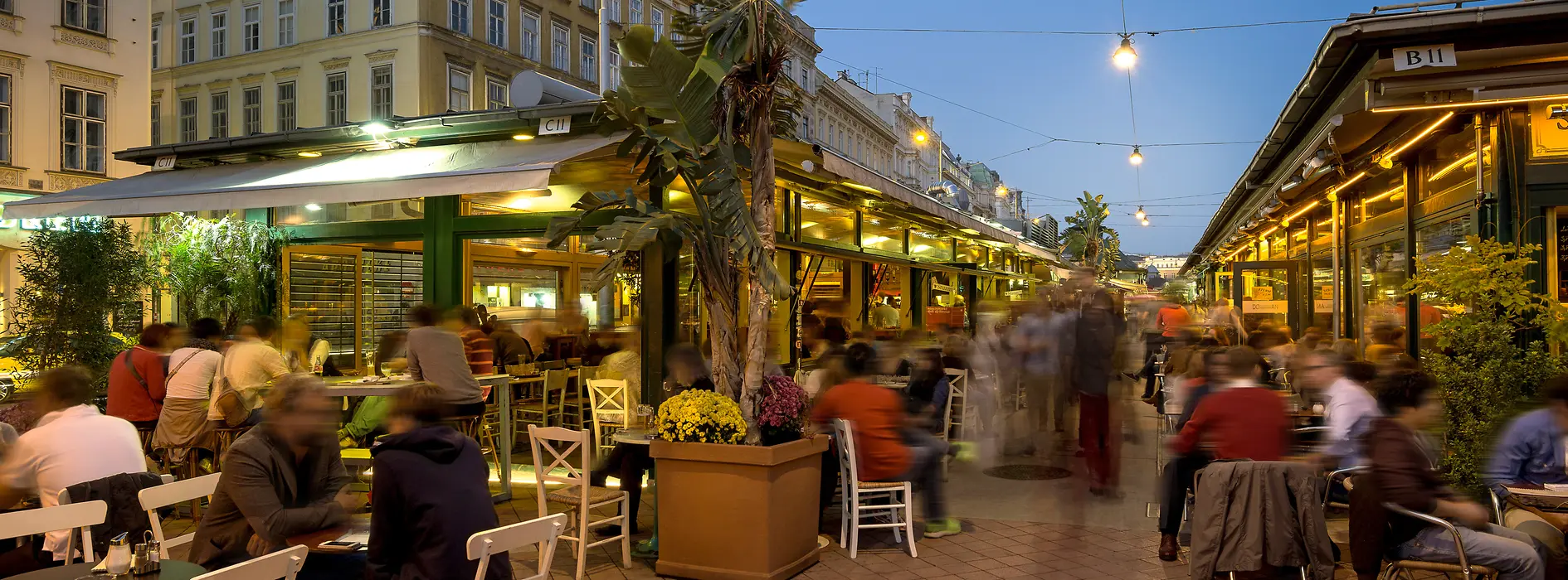 Buntes Treiben in den Lokalen am Naschmarkt, Außenansicht mit Leuten 