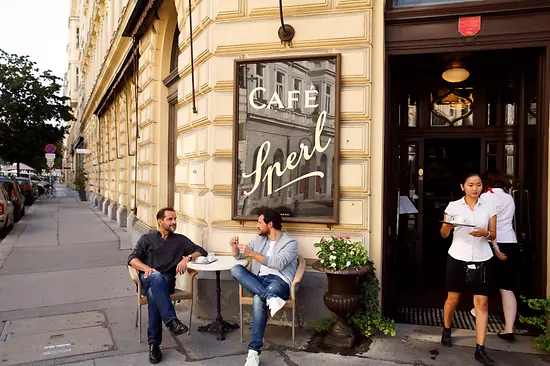 Two men sitting in front of a coffee house 