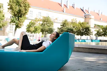 Woman lying on outdoor furniture in the inner courtyard of the MuseumsQuartier