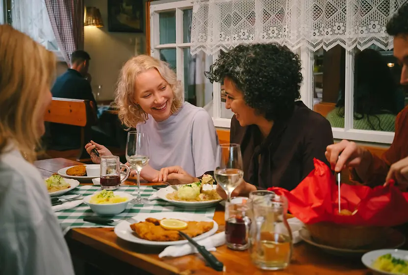 Gäste amüsieren sich und essen Wiener Schnitzel beim Heurigen