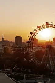 Ferris wheel in the Vienna Prater, Vienna skyline at sunset in the background