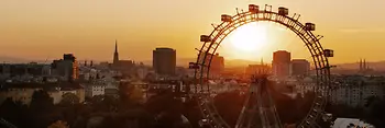 Riesenrad im Wiener Prater, im Hintergrund Wiener Skyline im Sonnenuntergang
