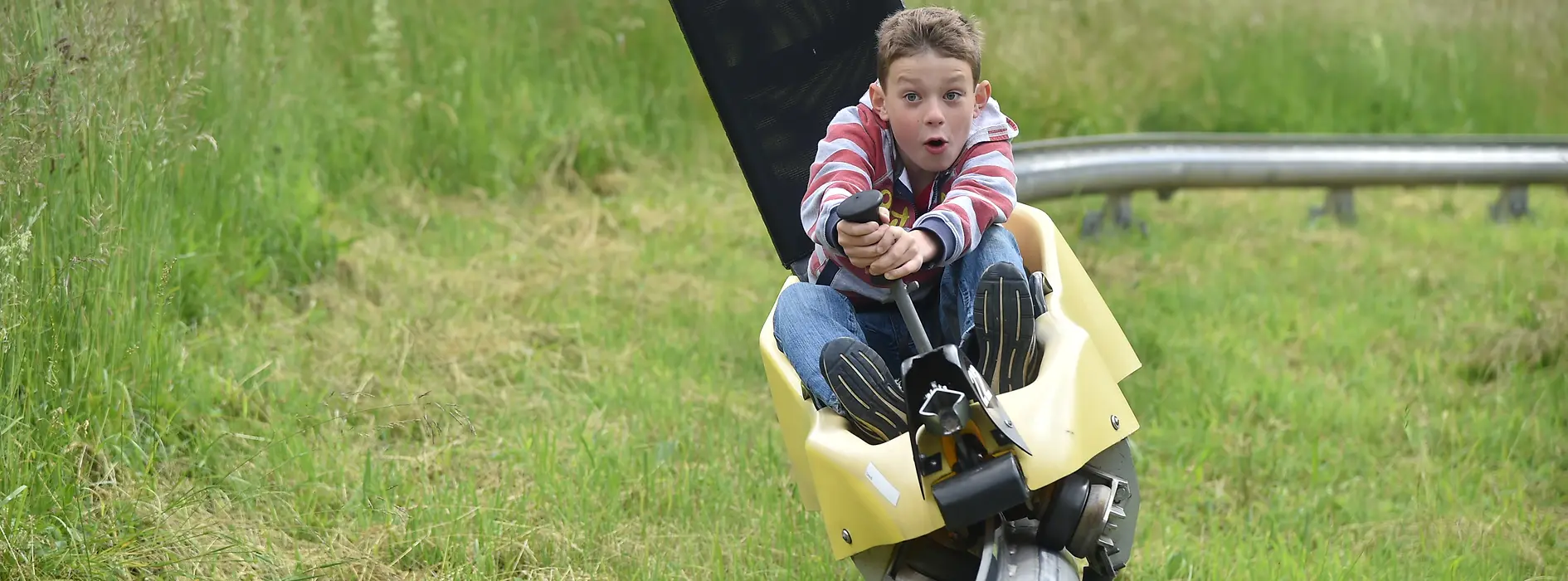 Bambino sulla pista da slittino estiva