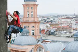 Mann klettert am Flakturm vor Wien-Panorama