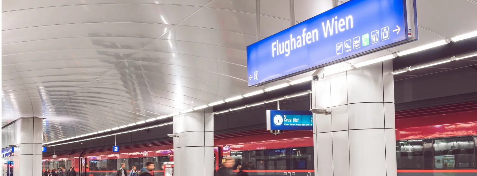 ÖBB Railjet im Flughafenbahnhof mit Reisenden im Vordergrund