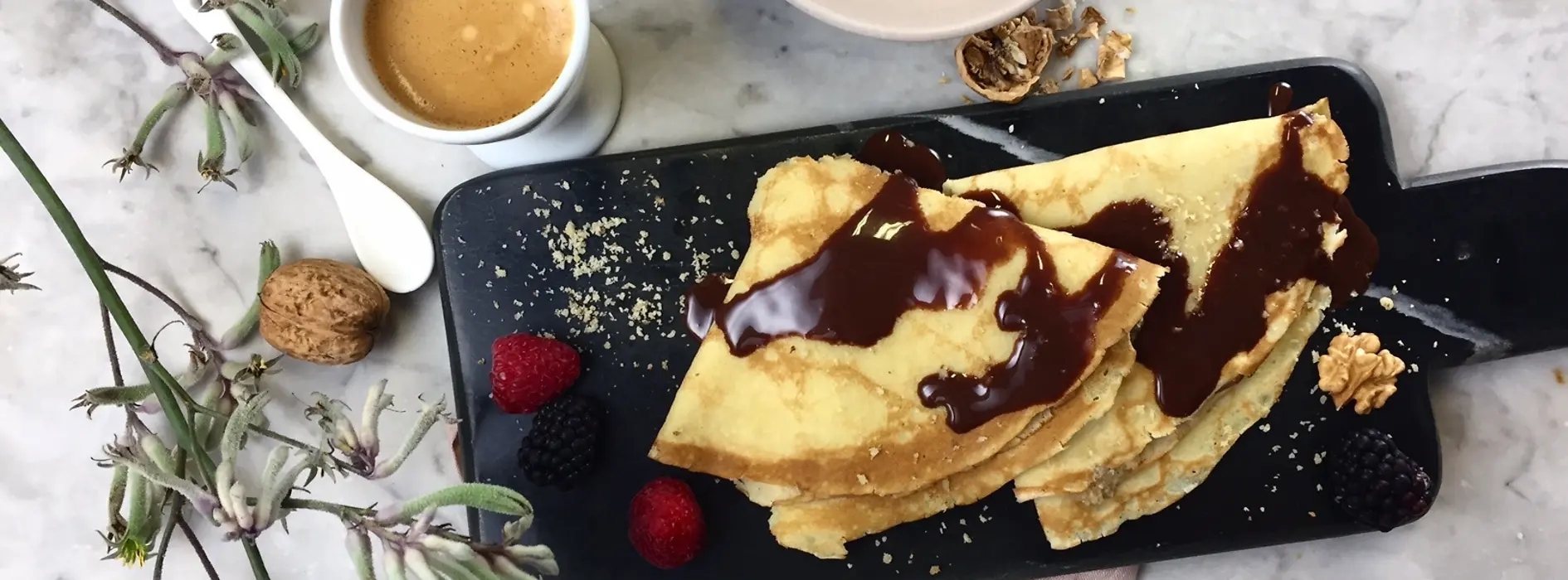 Zwei Schoko-Nuss-Palatschinken mit Kaffee und Besteck serviert