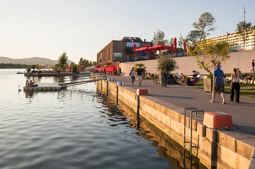 People walking along a pier on the Old Danube on a summer's evening