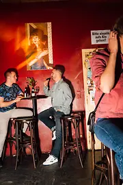 Two men chatting in the Marea Alta, a woman sitting at the bar