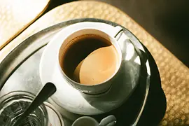 A silver tray with a cup of coffee and glass of water