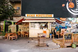 A sausage stand with seating furniture in front of it