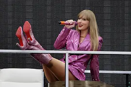 Taylor Swift on stage wearing a pink glitter dress and pink glitter boots