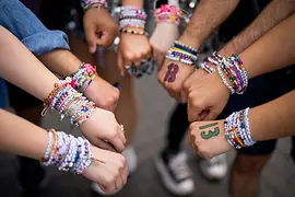 Nine hands of Taylor Swift fans with bracelets
