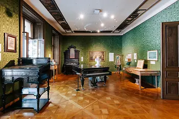 Salotto verde nell'appartamento Strauss con leggio, pianoforte e custodia per violino