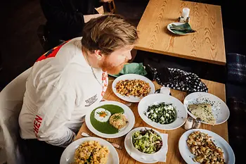 Chef Lukas Mraz in front of a crowd of plates of vegetarian dishes