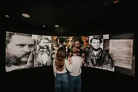 Ausstellungsraum mit riesigem gebogenen Screen, auf dem Strauss-Portraits zu sehen sind.