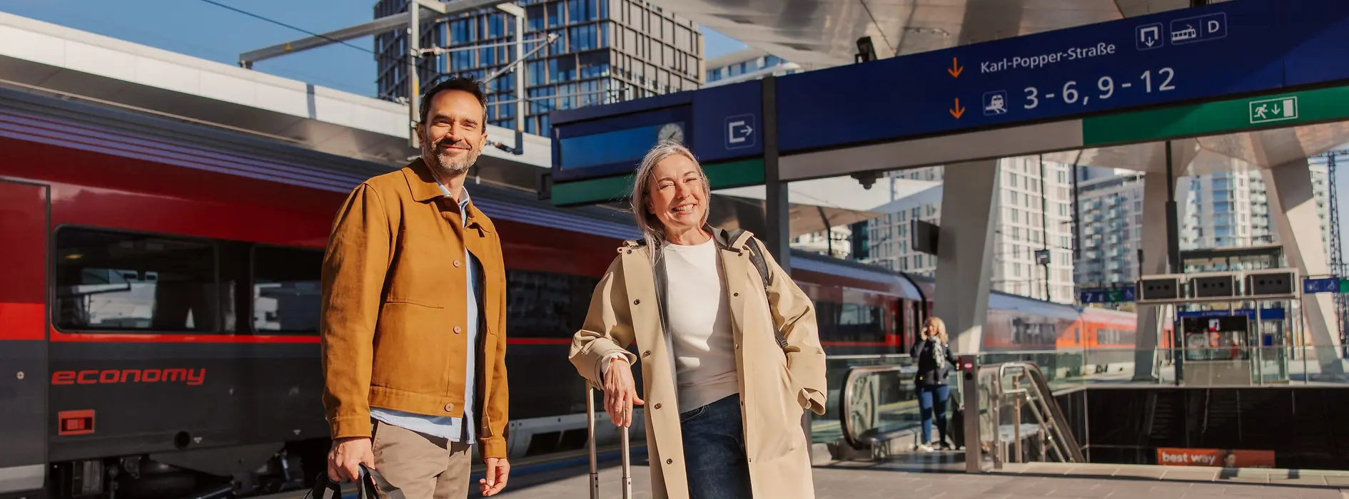 A couple is standing in front of a train on a platform at Vienna Main Station. 